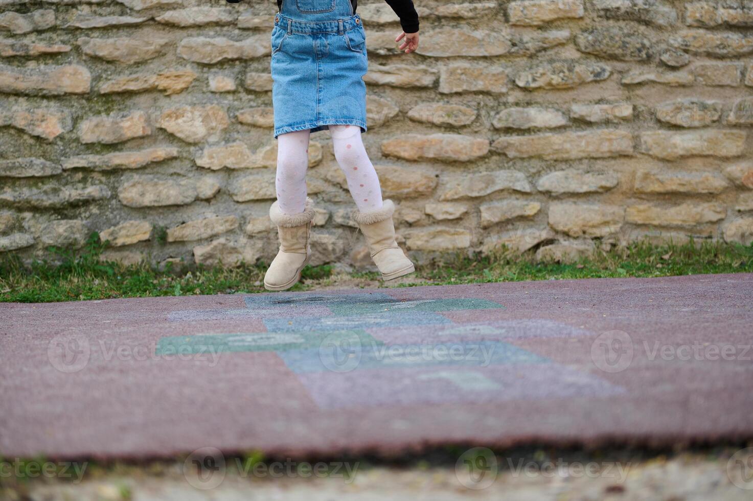 de cerca de un deportivo niño niña jugando rayuela, tomando vueltas saltando terminado cuadrícula marcado en patio de juegos. foto