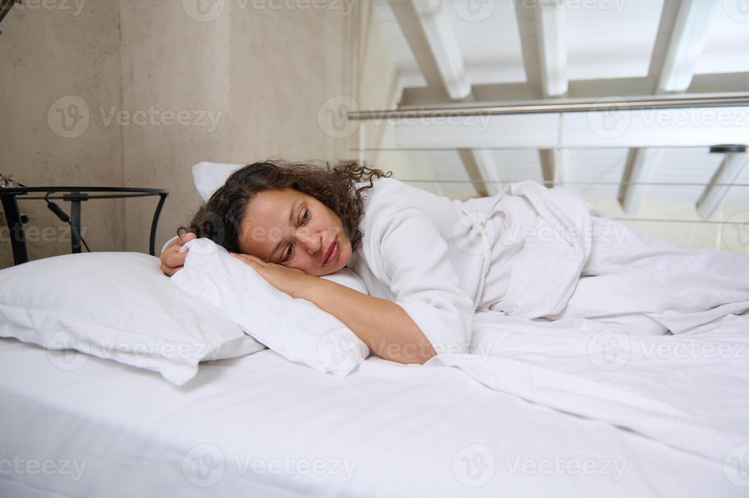 estresado medio Envejecido mujer acostado en cama a hogar y llanto. frustrado hembra sensación solitario foto