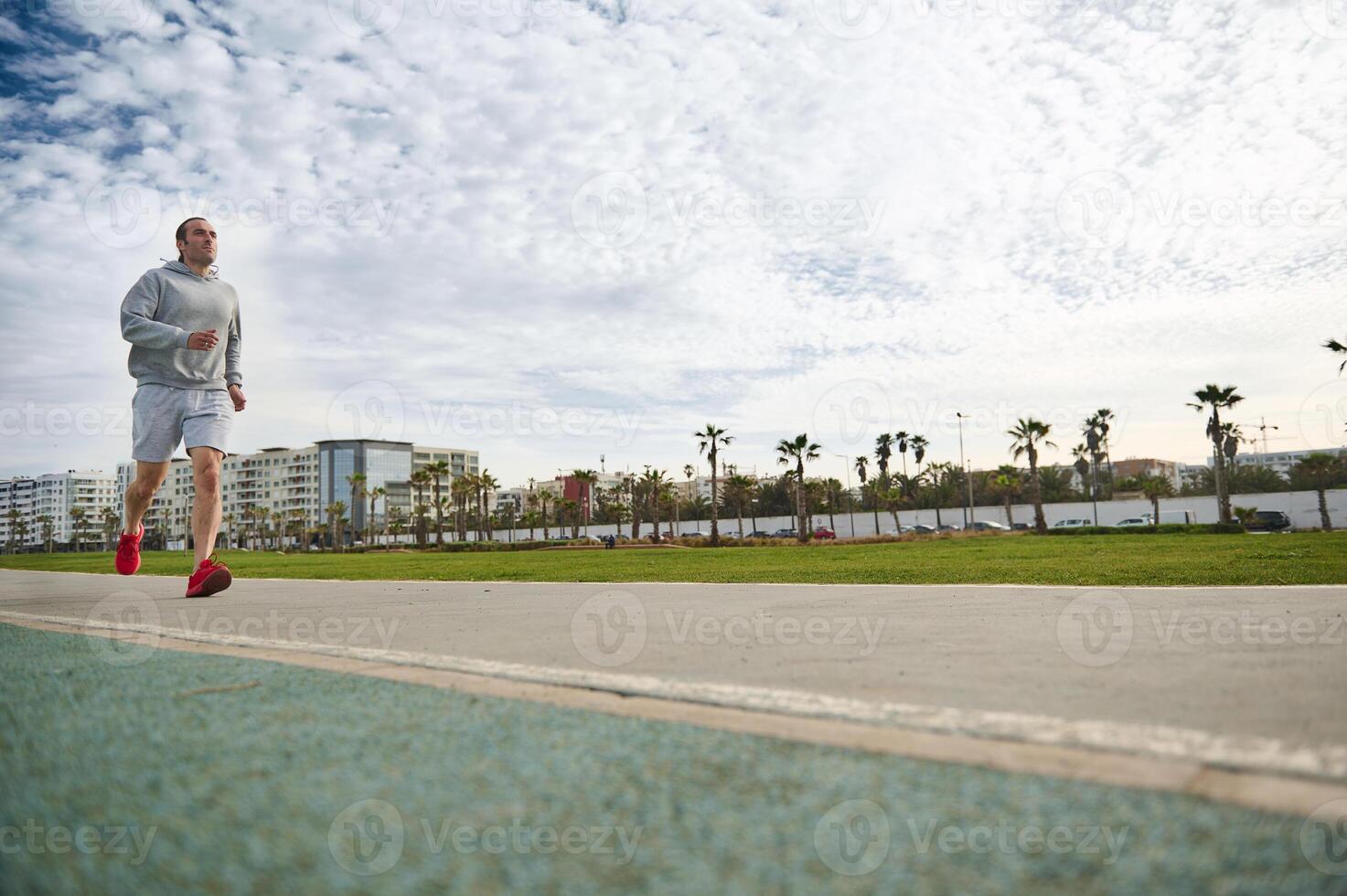 Active young man running in the city against modern urban buildings background. Copy advertising space on the treadmill photo