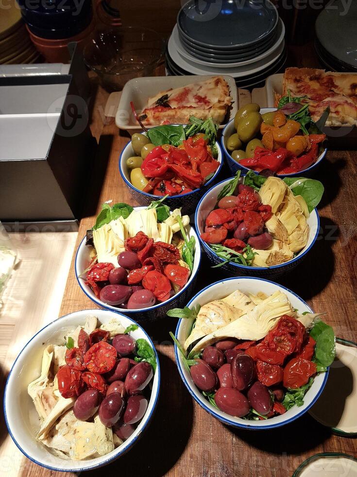 Artichokes, cherry tomatoes and olives with olive oil and salad and vegetarian lasagna. photo