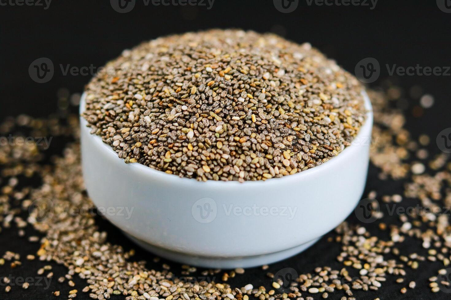 Chia seeds in a bowl on a black background. Selective focus. photo