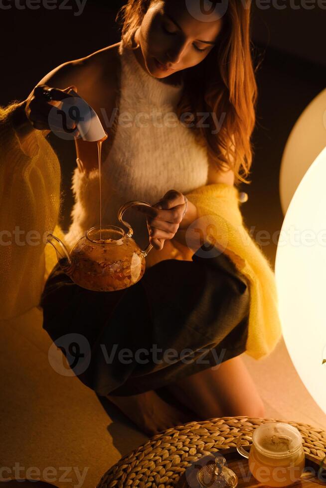 A young girl conducts an evening tea drinking procedure indoors. Relaxing tea party photo