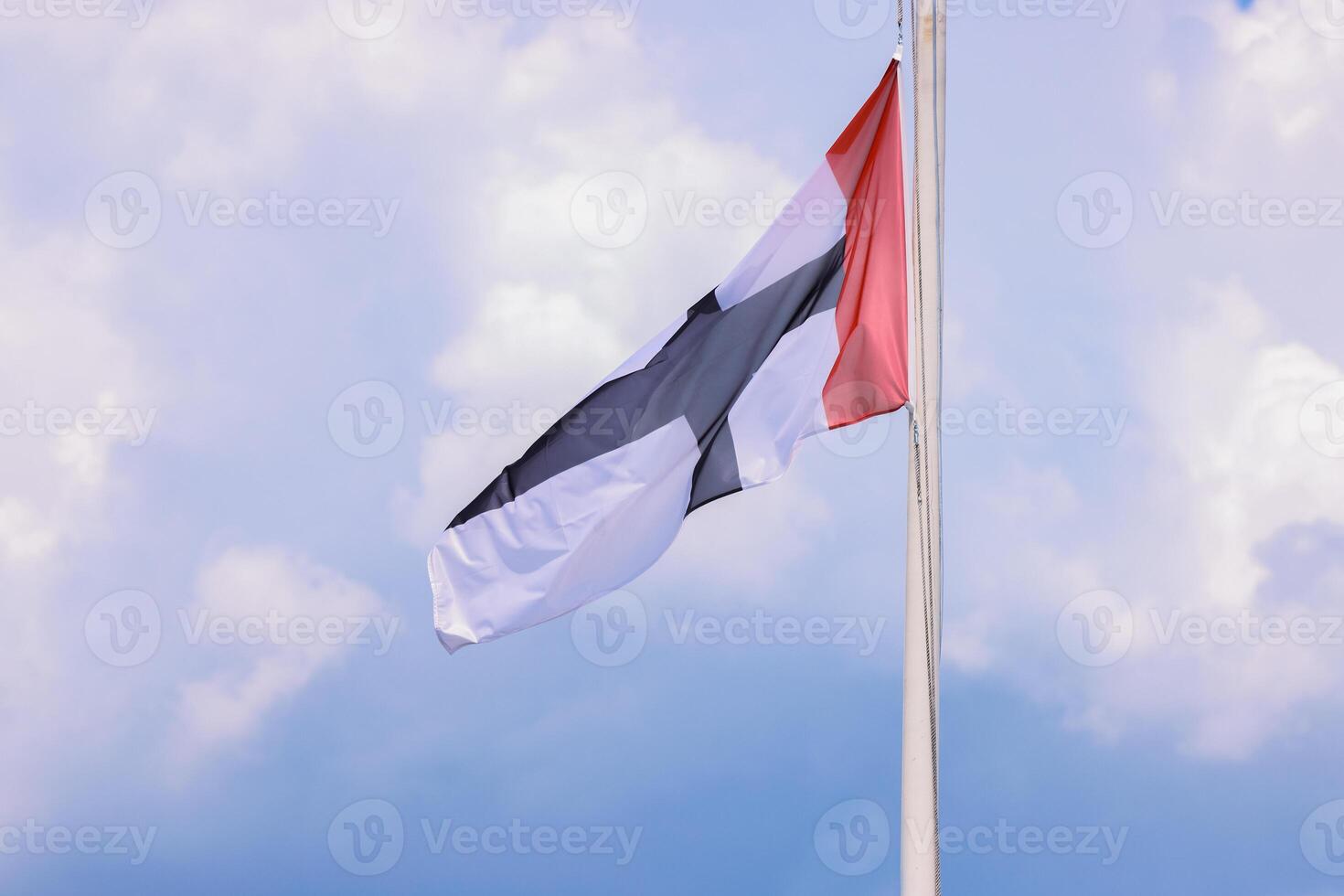 Flag of Constance City, Germany, Baden-Wuerttemberg. Flying in the wind silky fabric Flag of Konstanz on the flagpole. isolated on blue cloudy sky background. View from the touristic boat. Copy space photo