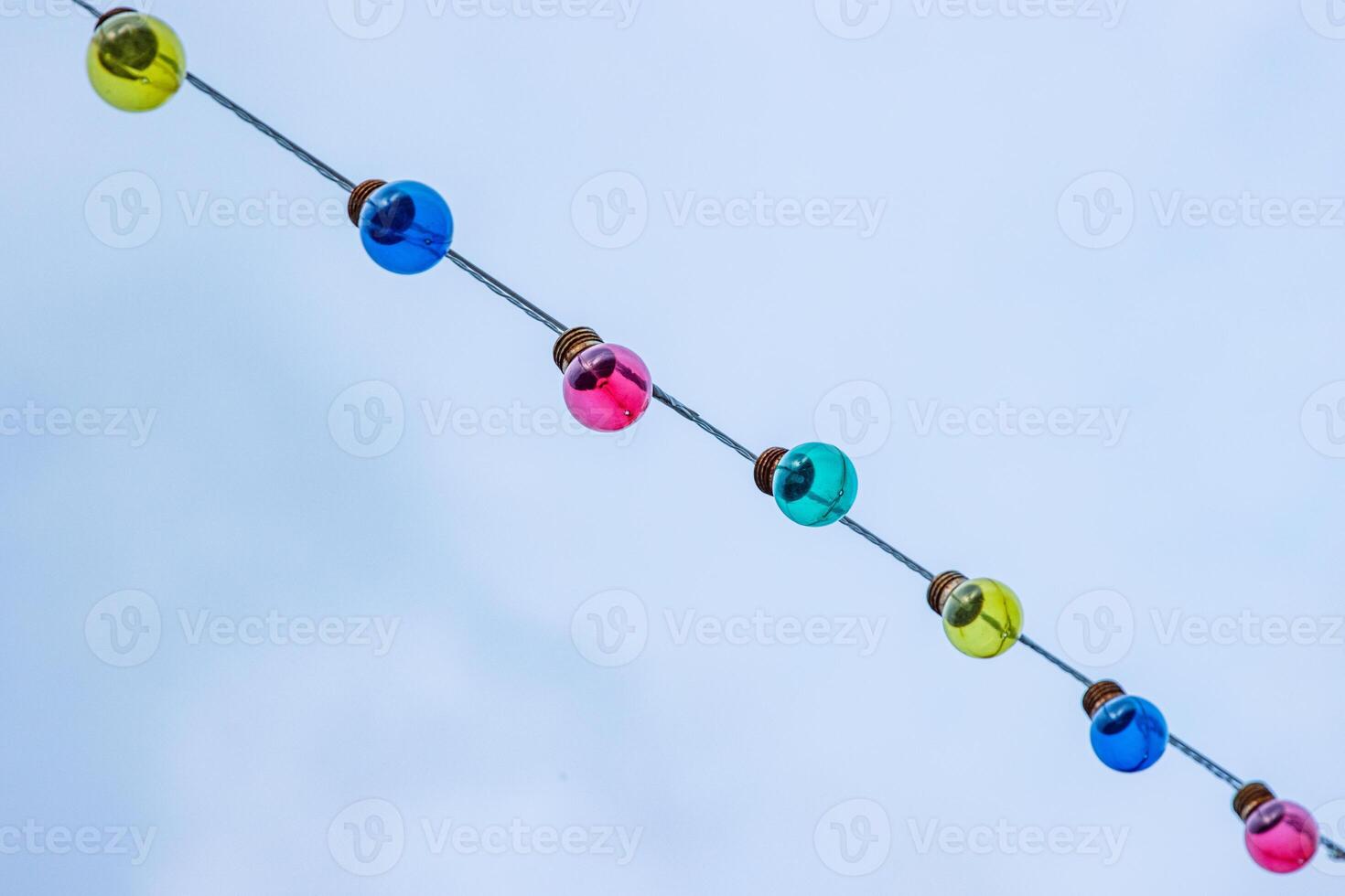 Straight diagonal line of garland light bulbs on cloudy sky background. Wedding ceremony decoration. Backdrop, wallpaper. Minimalistic conceptual simple graphic design idea for ads, posters, banners photo