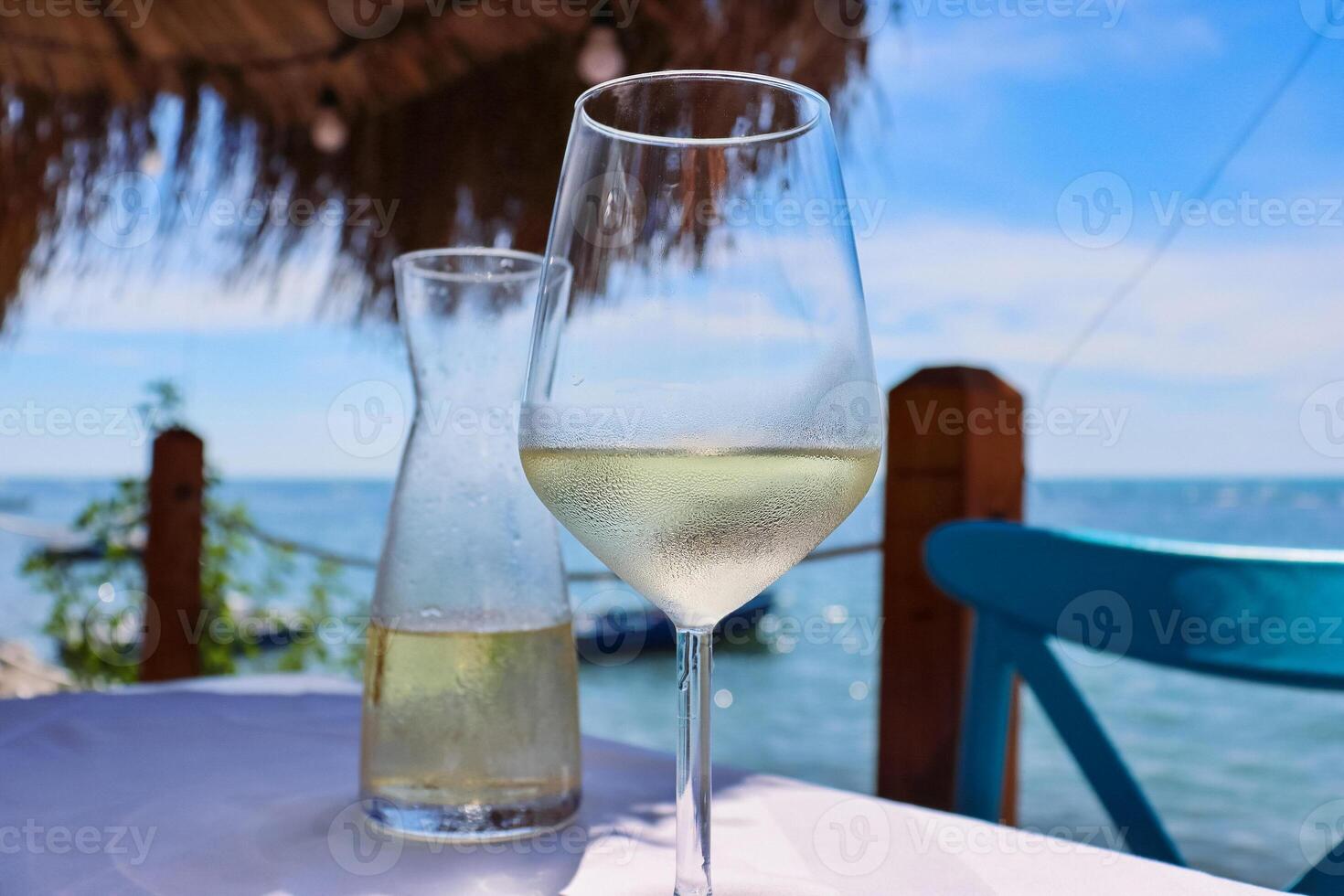 Glass and the pitcher of ice cold vine on the table in the 2 Kitarrat Arome Deti restaurant on the Adriatic beach in Durres. Albania.  Beautiful sunny summer day. Blue sky and the sea. Selective focus photo