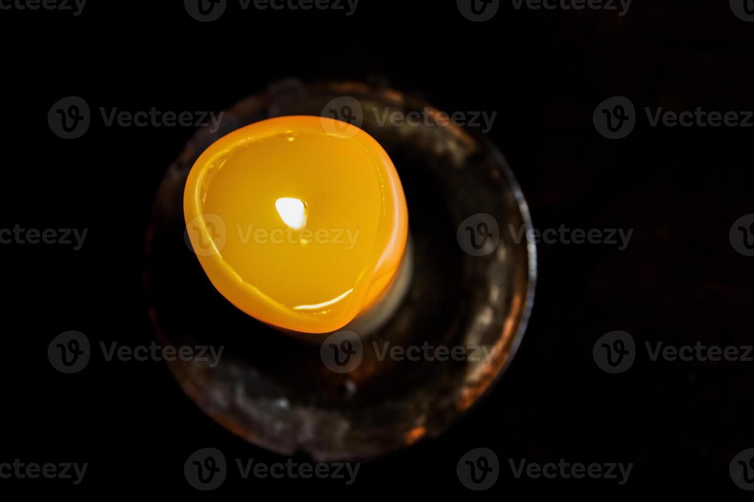 Lit candle on the wooden table. Burning candle in the candleholder. Burning light. hot fire. Cozy atmosphere. Copy Space. Backlight from the window. Top view. Selective focus. photo