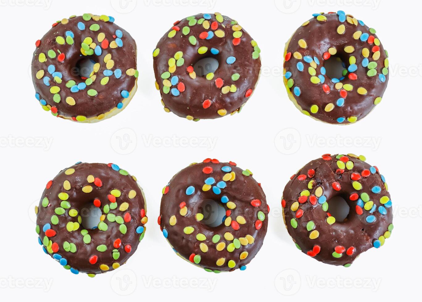 Set of six tasty chocolate donuts with smarties on white background. 6 Doughnut decorated with colorful nibble on top. Birthday party.  Hanukkah celebration concept. Isolated. Top view photo