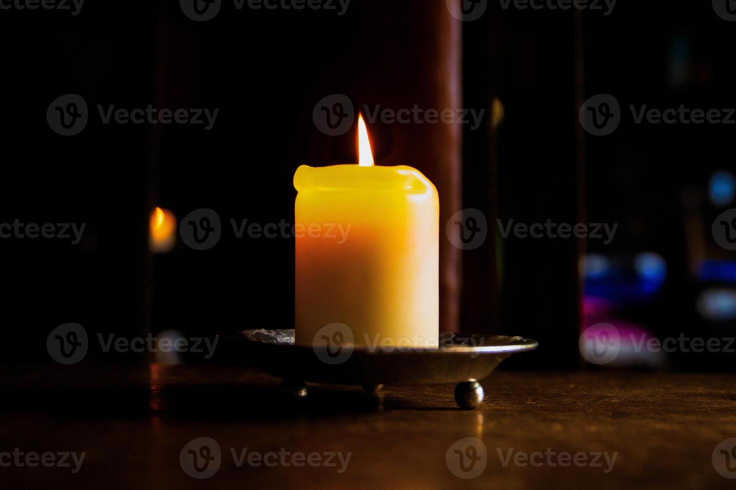 Lit candle on the wooden table. Burning candle in the candleholder. Burning light. hot fire. Cozy atmosphere. Selective focus. Backlight from the window. photo