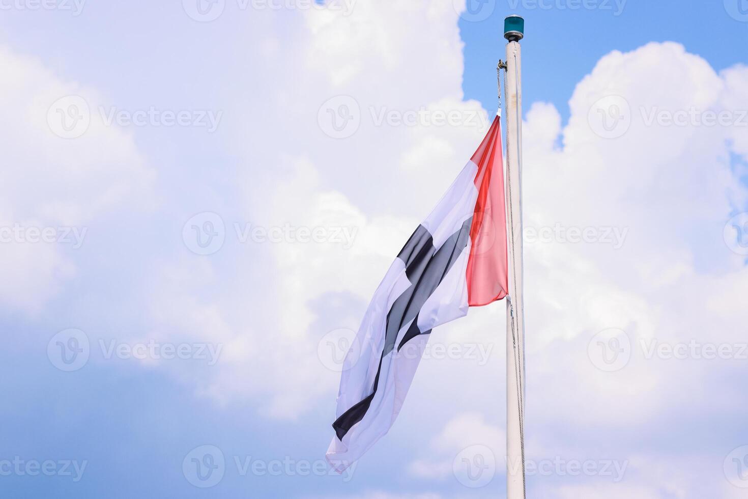 Flag of Constance City, Germany, Baden-Wuerttemberg. Flying in the wind silky fabric Flag of Konstanz on the flagpole. isolated on blue cloudy sky background. View from the touristic boat. Copy space photo