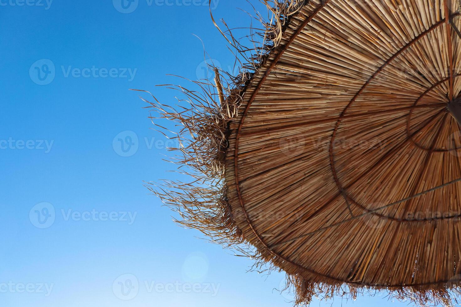 Albania. Durres. Closeup of the straw sun umbrella on the Adriatic beach. A beautiful sunny day and the blue sky on the background.  Straw texture. Copy space. Selective focus. photo