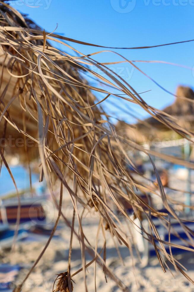 Albania. Durres. Closeup of the straw sun umbrellas on the beach shoreline. A beautiful sunny day and the blue sky on the Adriatic Sea. Selective focus. photo