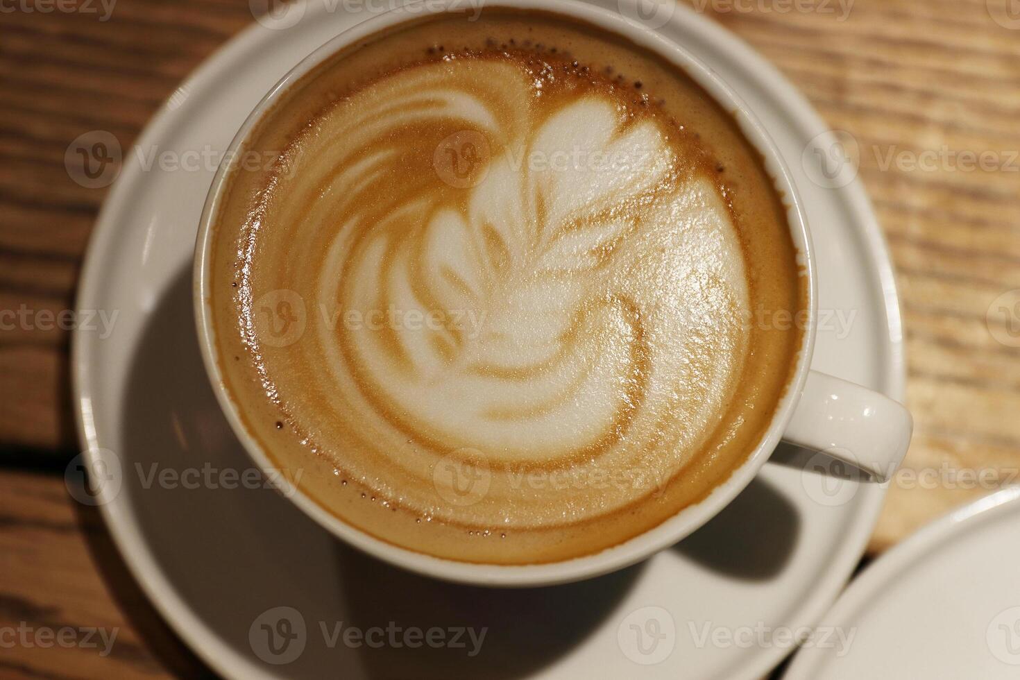A cup of latte, cappuccino or espresso coffee with milk put on a wood table in cafe. Cream Foam on the top of cup of coffee. Barista Coffee latte art. Top view photo