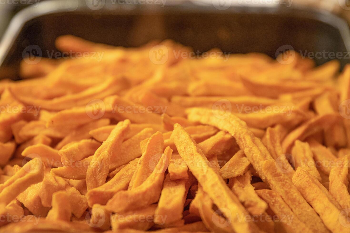 Yummy French fries in the metal tray. Potato chips on the counter at the street market. Selective focus. Side view. Bokeh. photo