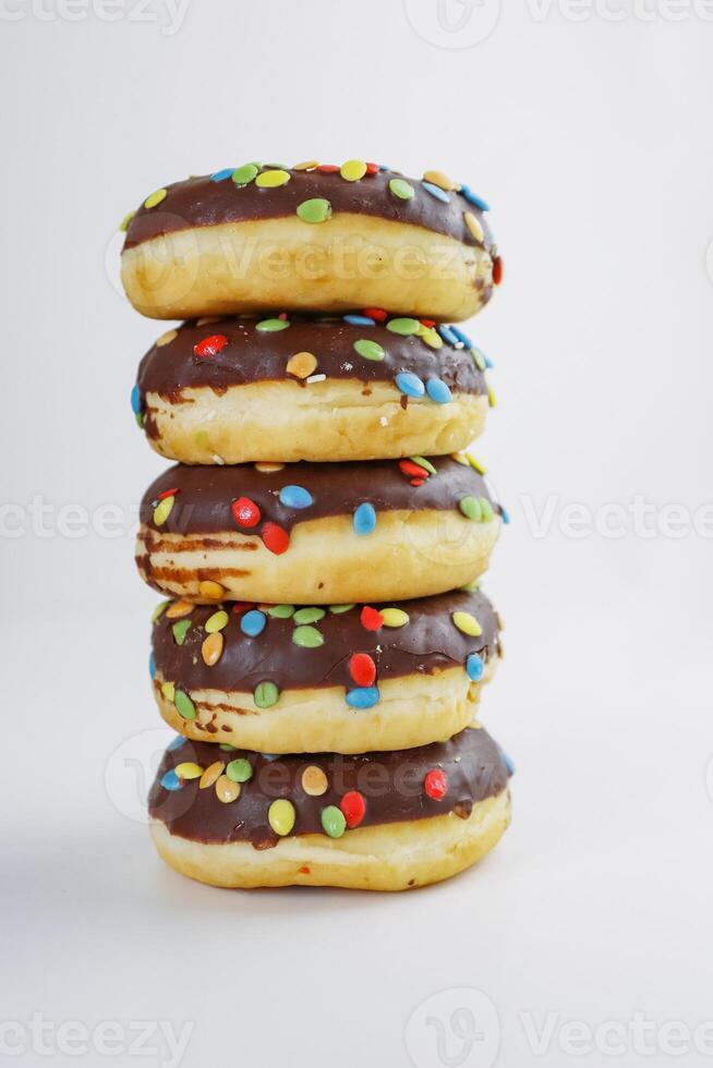 A stack of doughnuts glazed with chocolate and colorful smarties. Pile of 5 donuts isolated on a white background. Side view. Copy space photo