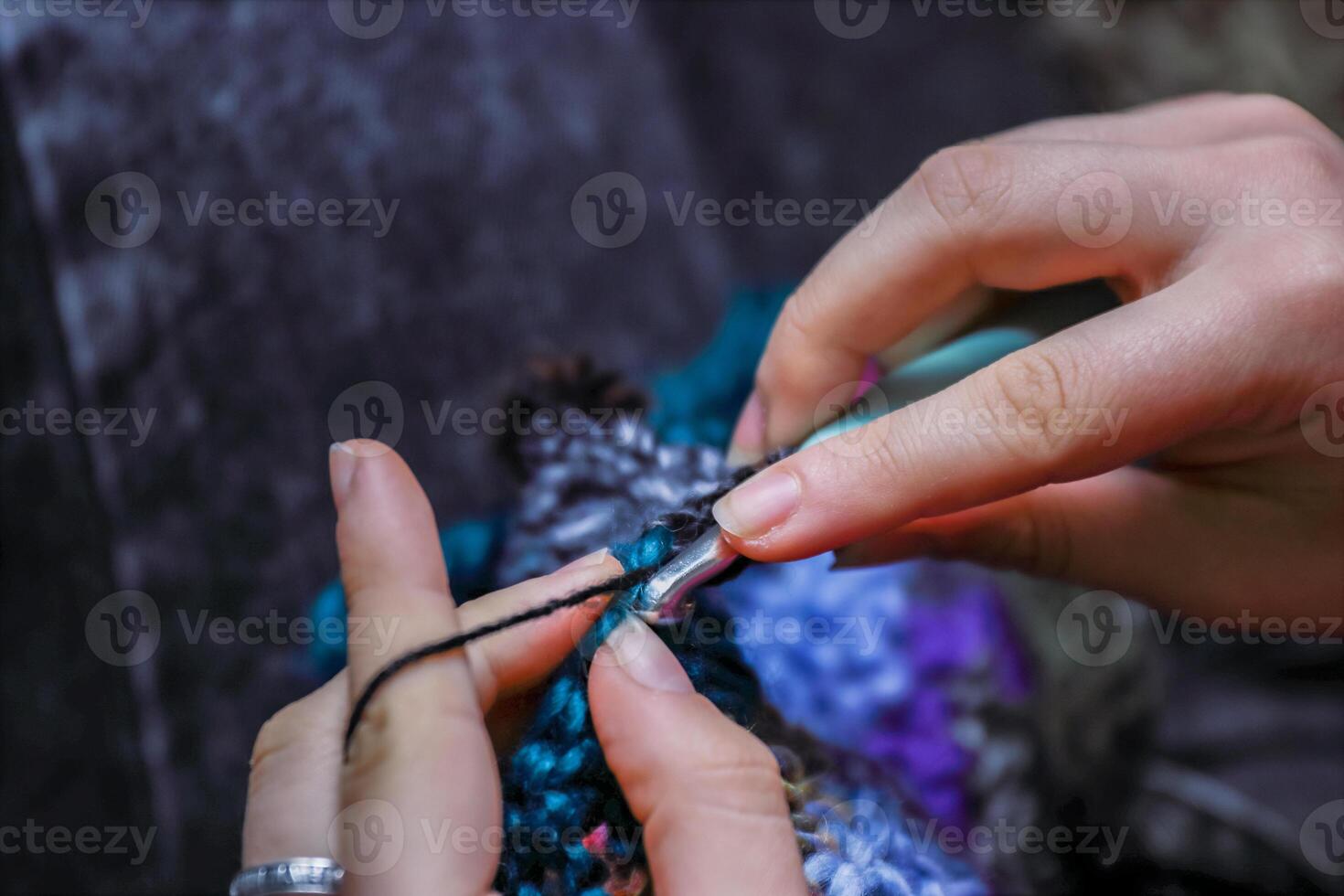 Skillful fingers of a young lady holding crochet hook and wool thread. Girls hands crocheting handmade jacket. Handcraft hobby, creating for kraft art or farmer fashion market. Selective focus photo