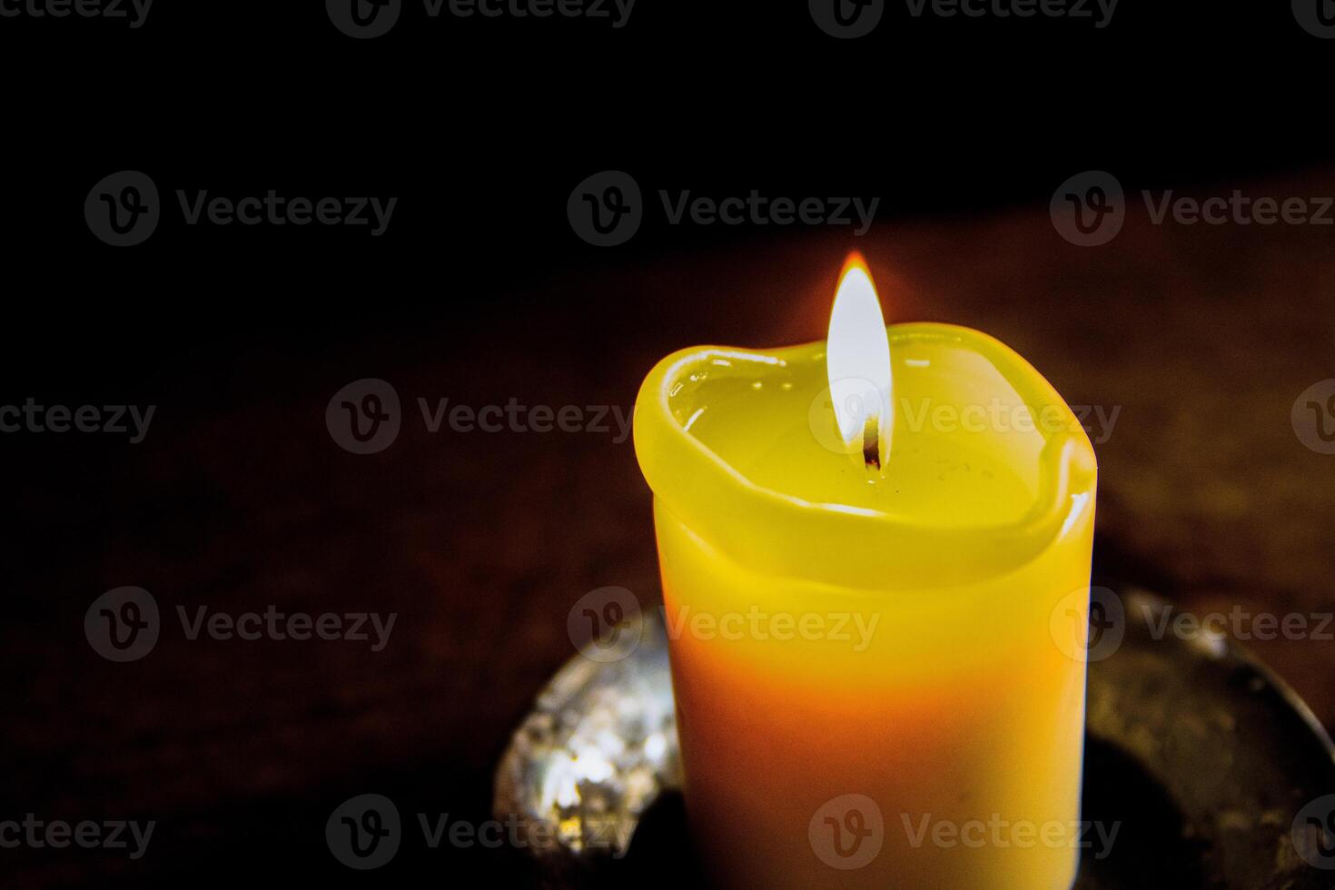 Lit candle on the wooden table. Burning candle in the candleholder. Burning light. hot fire. Cozy atmosphere. Selective focus. Backlight from the window. photo