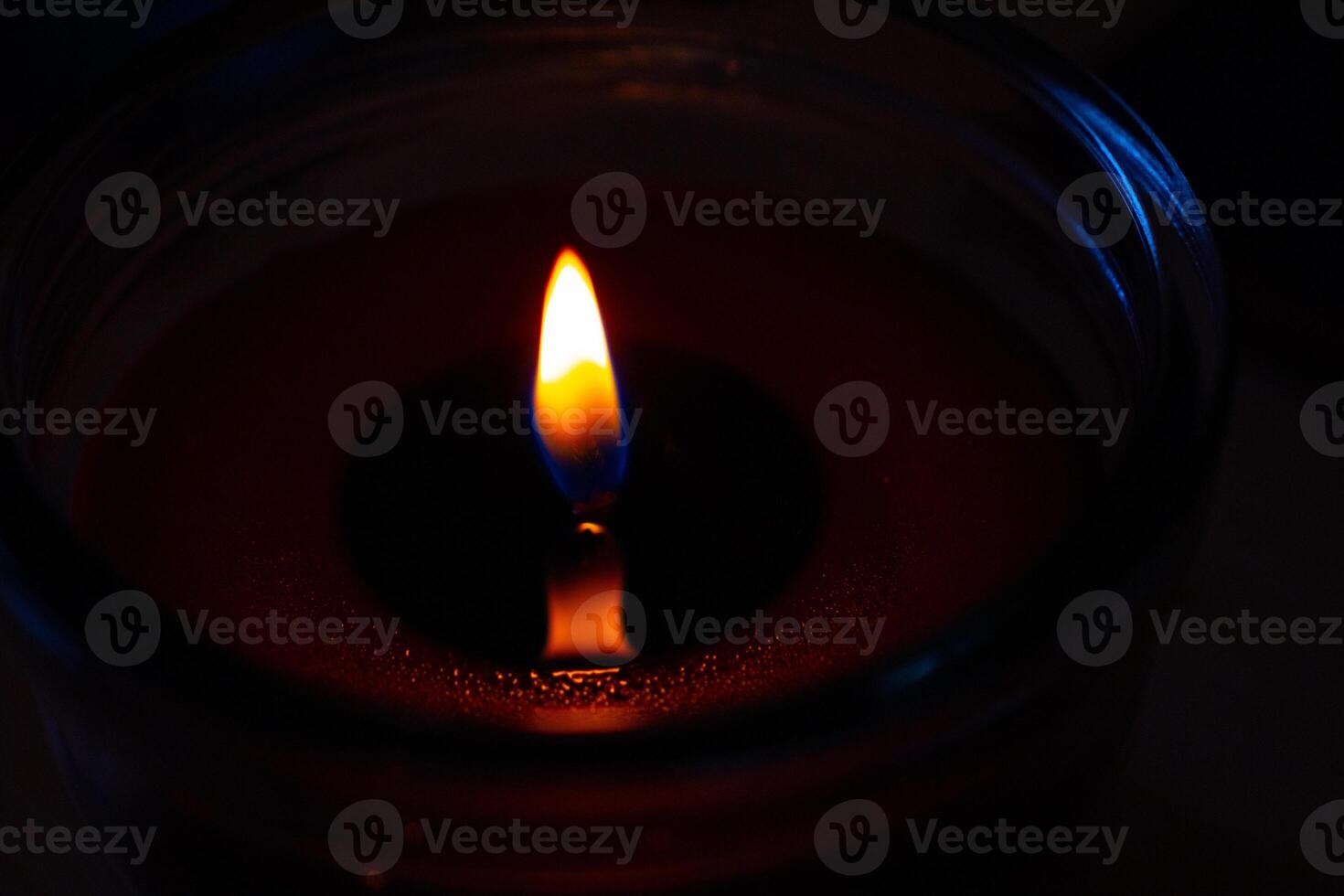 Beautiful burning candle with the flame reflection on the melted wax Closeup. Oil lantern. Blue splash on dark black background. Minimalistic concept. Graphic design, poster. Copy text space. Bokeh. photo