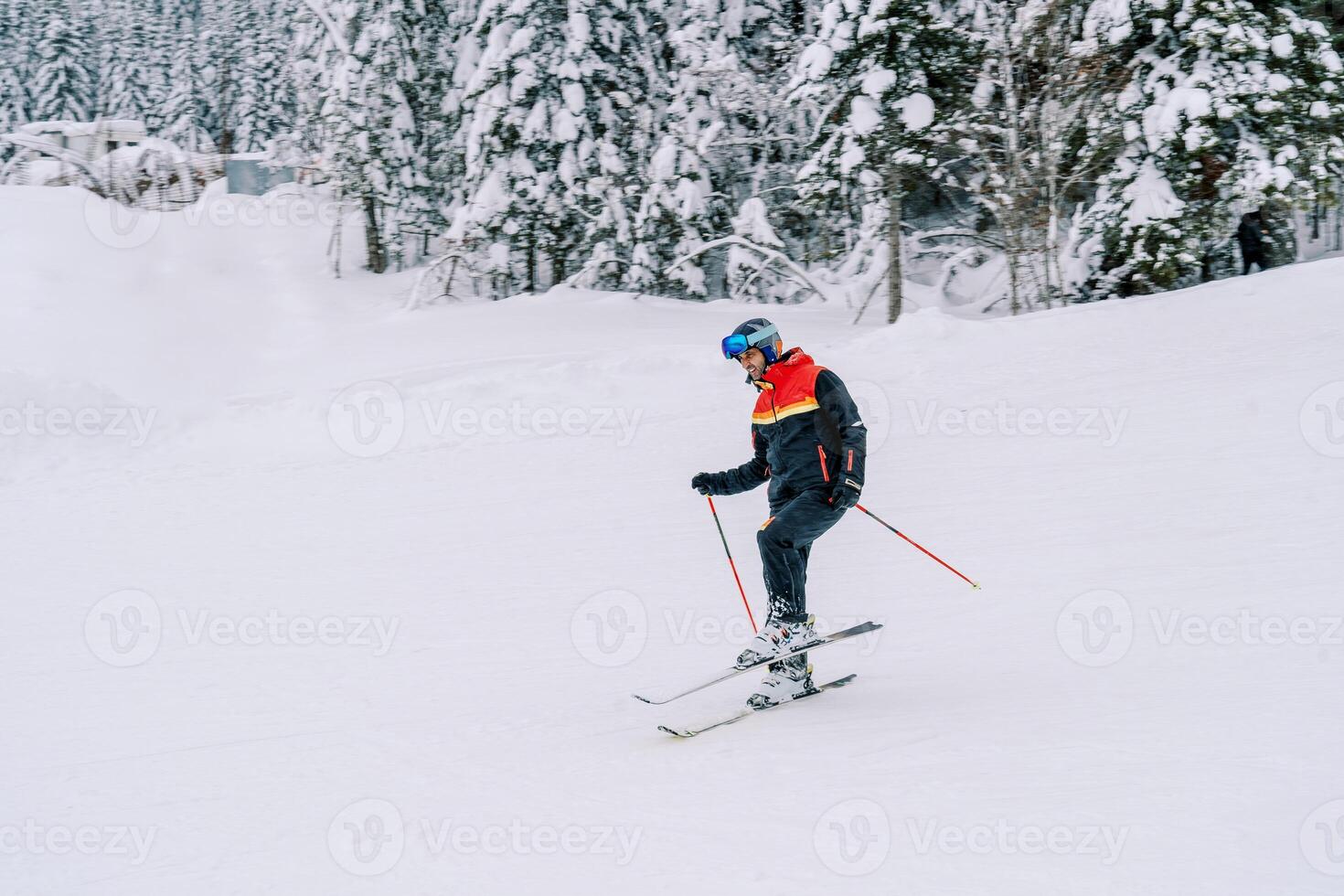 Man in a ski suit is skiing with his leg bent at the knee on the slope of a snowy mountain photo