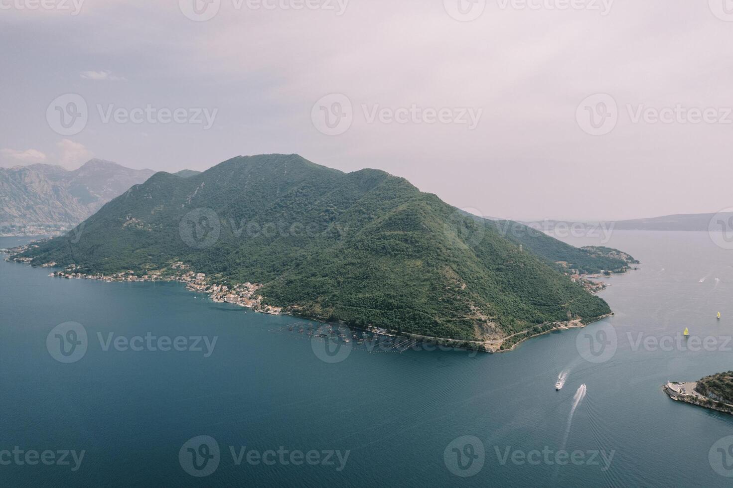 Yachts sail along the Bay of Kotor past the green mountain range. Aerial view photo