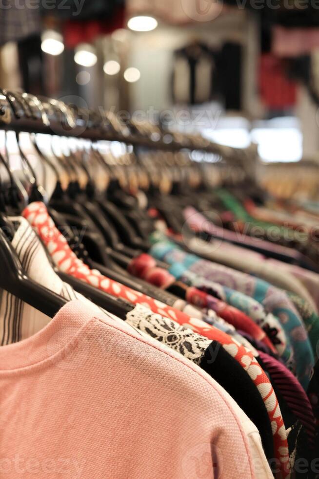 un fila de ropa colgando en un estante en un almacenar. adecuado para Moda y Al por menor conceptos foto