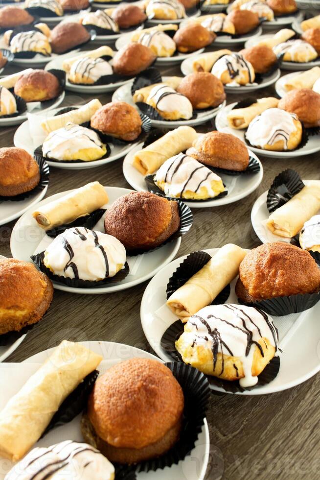 Bunch of snack cakes on plate. Many rows of plates with buffet snacks. photo