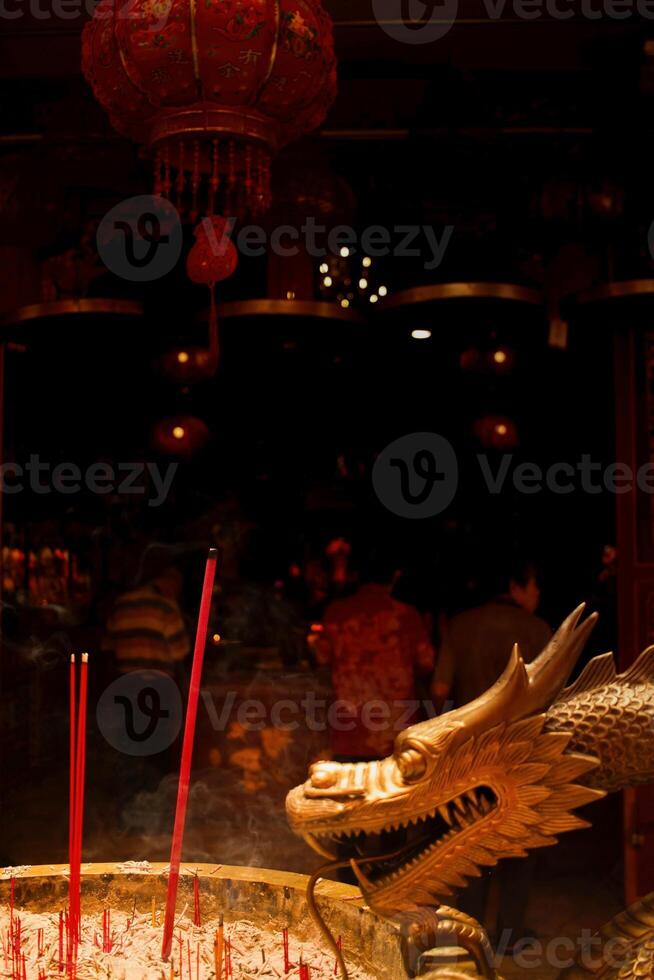 Burning prayer sticks fill the room with billowing smoke with dragon decorations on the sides at the Chinese New Year celebration. Eng An Kiong Temple, Malang, Indonesia photo