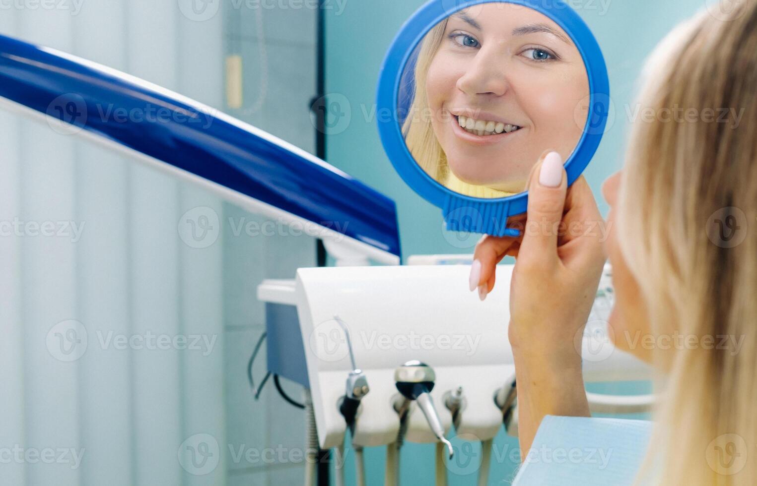 The girl smiles and looks in the mirror in dentistry photo