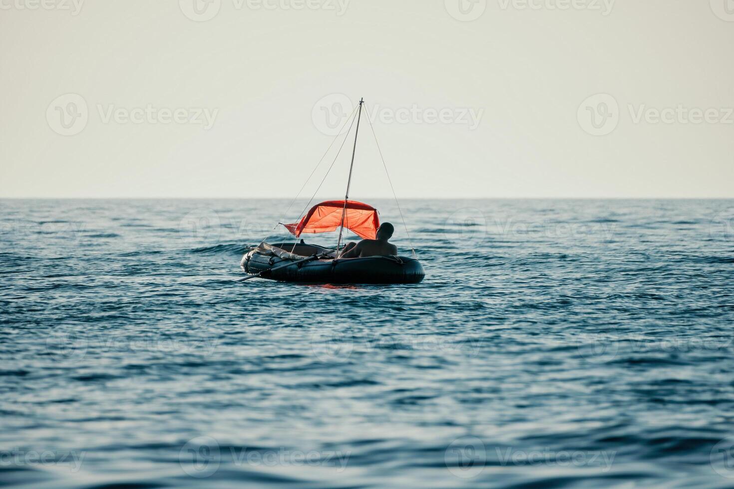 Fisher sea boat. Tourist maneuvering an inflatable boat while fishing in a life jacket, with the beautiful sunset sea in the background. a relaxing fishing trip. photo