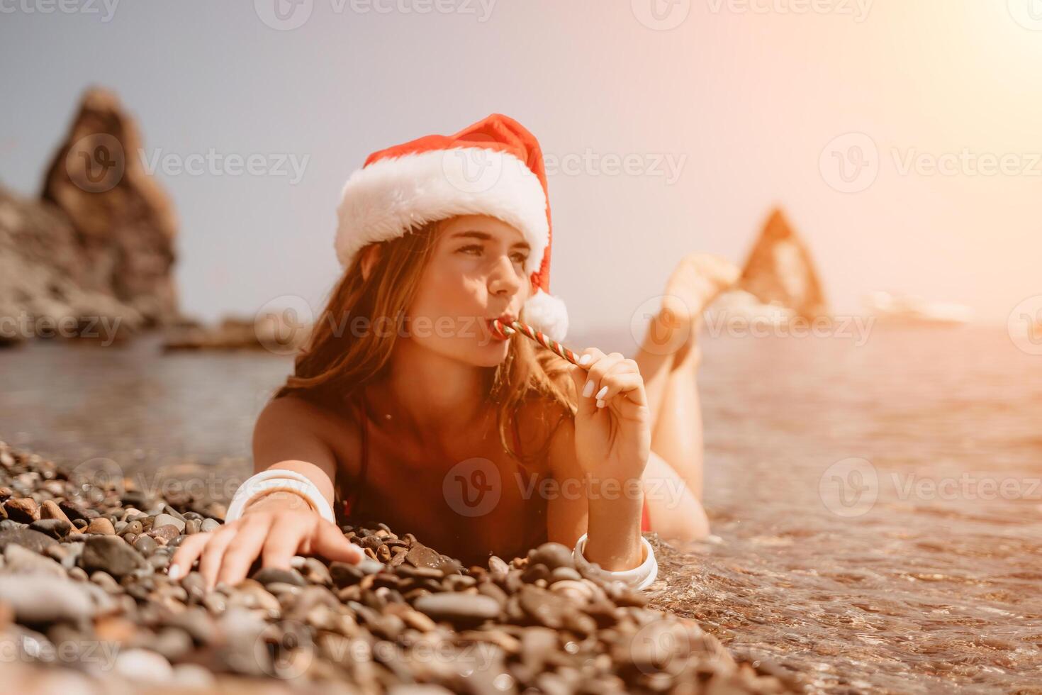 Woman travel sea. Happy tourist enjoy taking picture on the beach for memories. Woman traveler in Santa hat looks at camera on the sea bay, sharing travel adventure journey photo