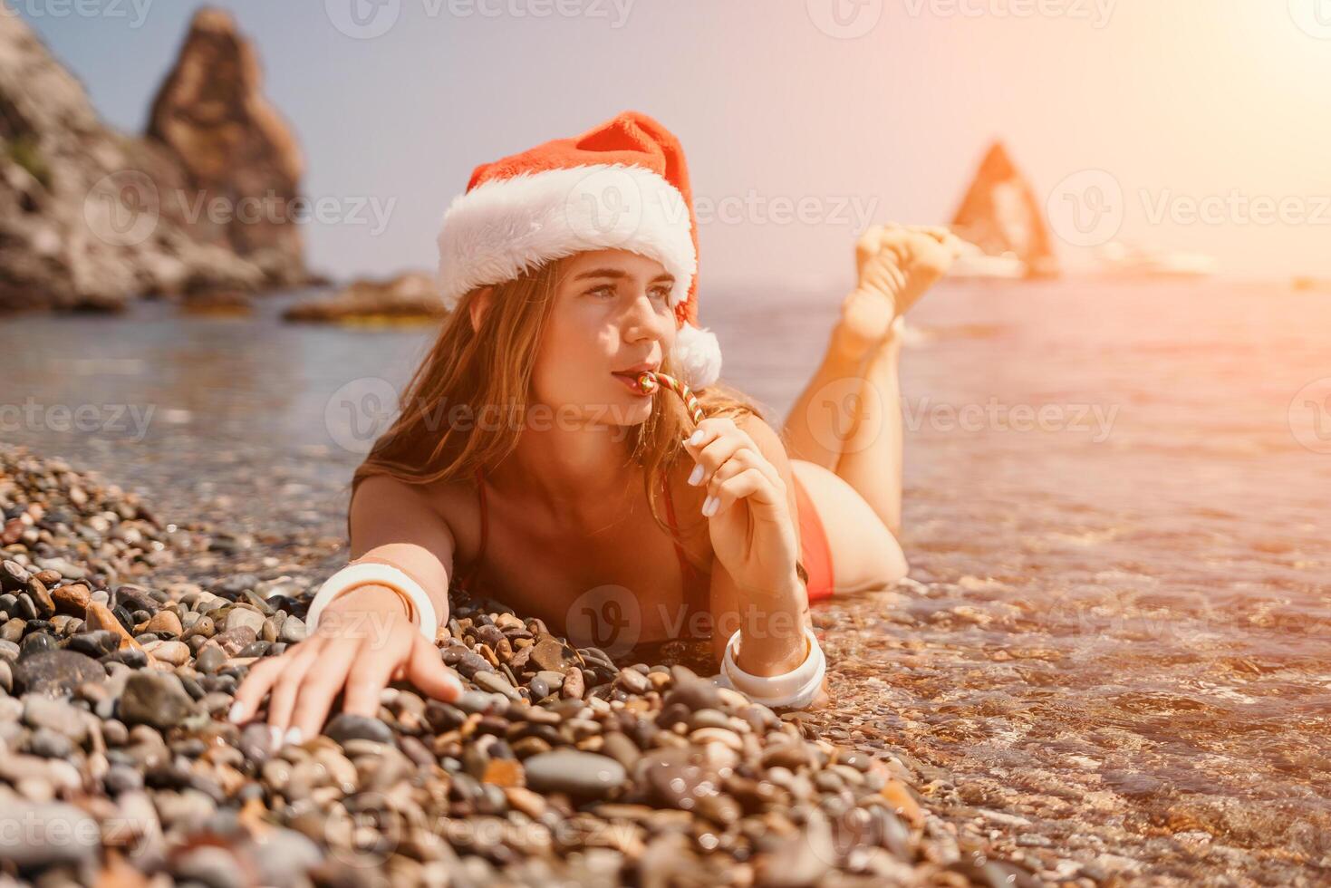 Woman travel sea. Happy tourist enjoy taking picture on the beach for memories. Woman traveler in Santa hat looks at camera on the sea bay, sharing travel adventure journey photo