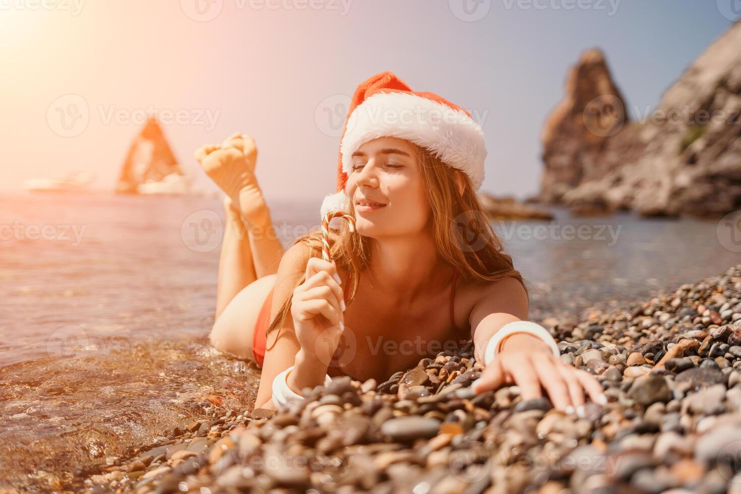 Woman travel sea. Happy tourist enjoy taking picture on the beach for memories. Woman traveler in Santa hat looks at camera on the sea bay, sharing travel adventure journey photo