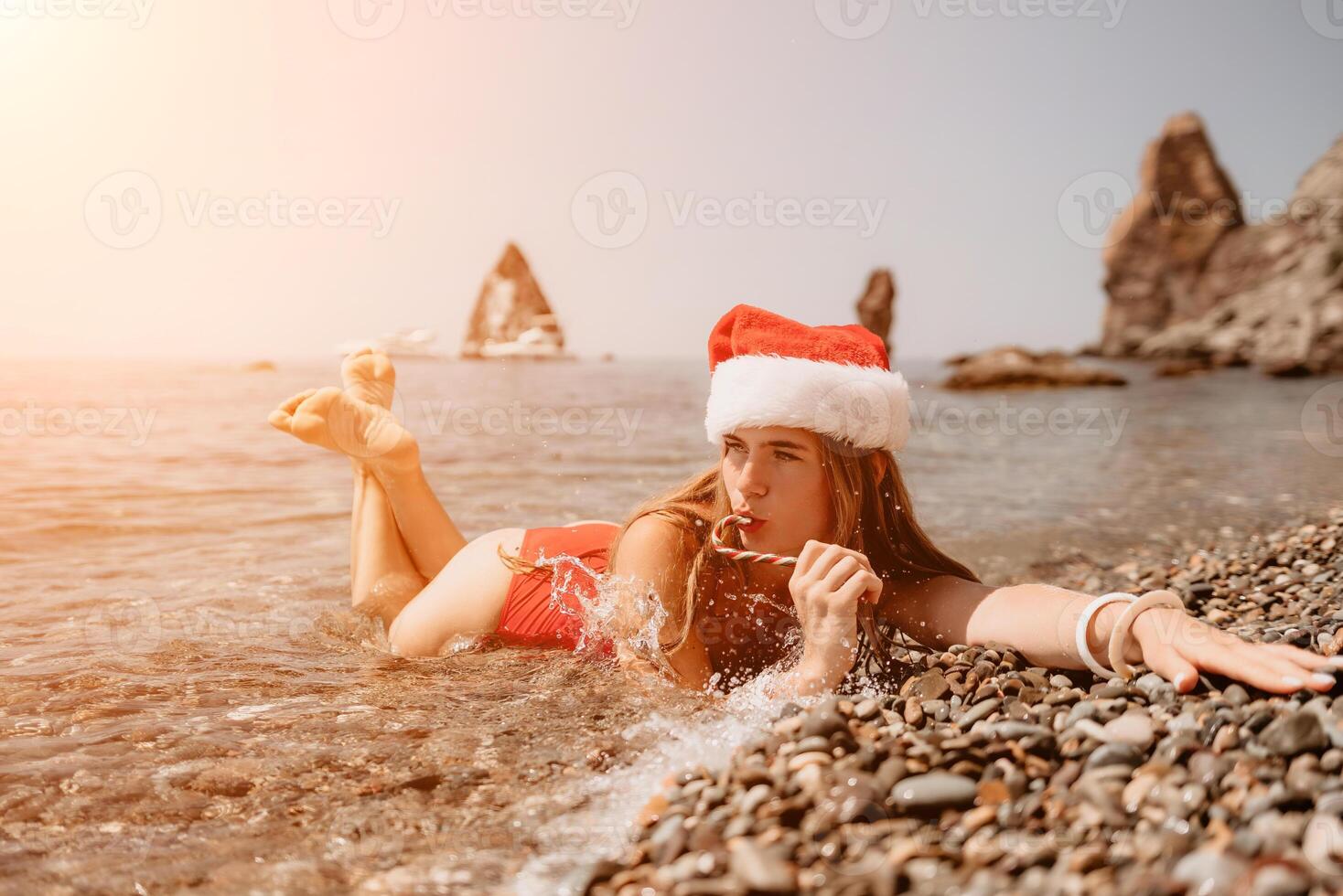 Woman travel sea. Happy tourist enjoy taking picture on the beach for memories. Woman traveler in Santa hat looks at camera on the sea bay, sharing travel adventure journey photo