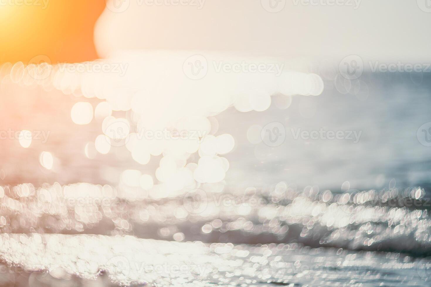 Blurred golden sea at sunset. The sun reflects and sparkles on the waves with bokeh, illuminating the golden sea. Holiday recreation concept. Abstract nautical summer ocean sunset nature background. photo