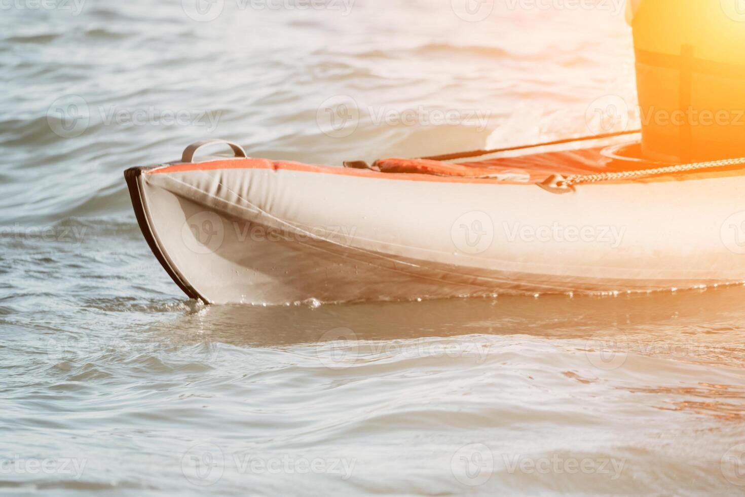 Happy couple kayaks in an inflatable kayak on the sea at sunset. Couple kanoeing in the sea near the island with mountains. People kayaking in life jackets sail. Back view photo