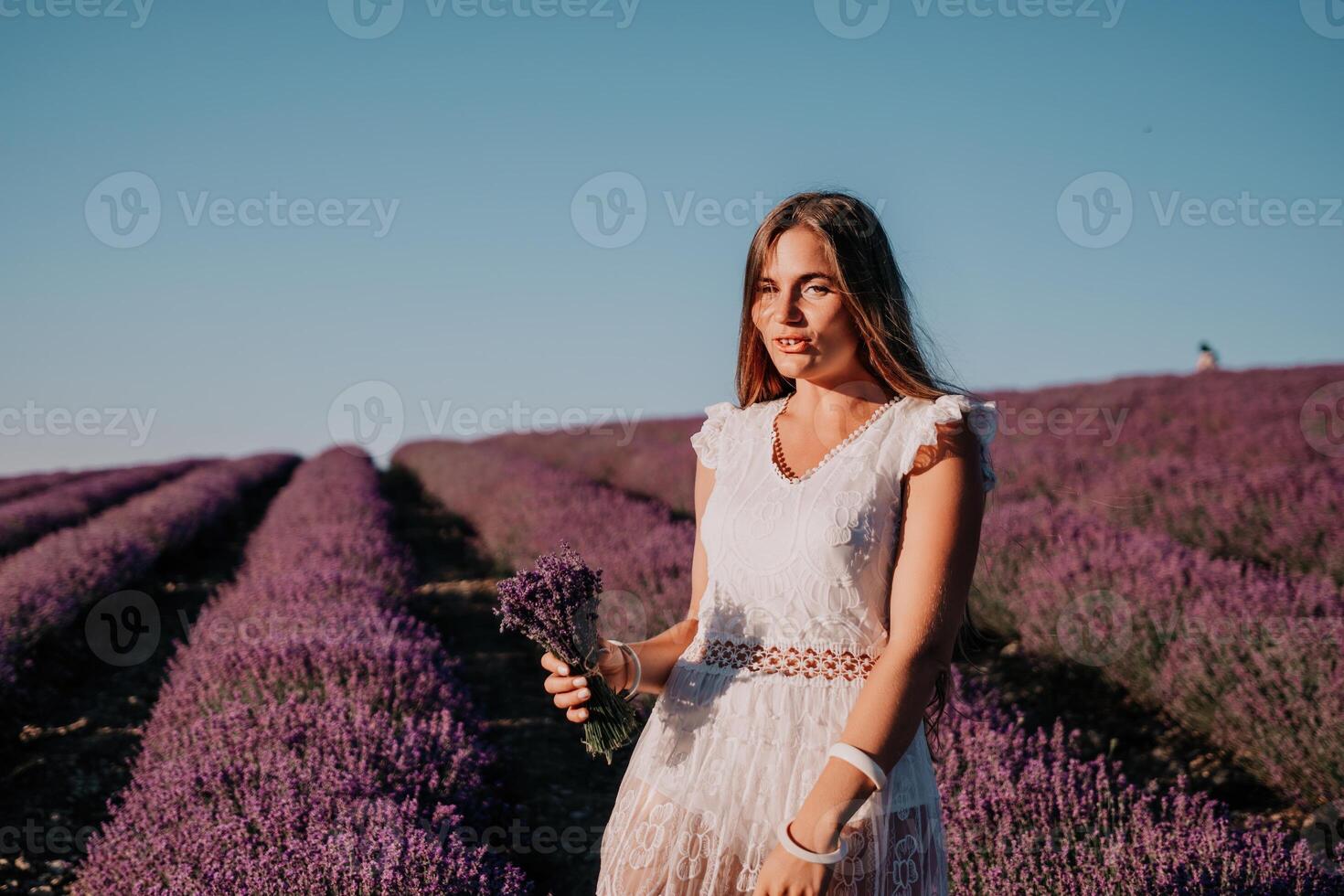 mujer lavanda campo. contento despreocupado mujer en un blanco vestir caminando en un lavanda campo y oliendo un lavanda ramo de flores en puesta de sol. ideal para calentar y inspirador conceptos en pasión de viajar y viajar. foto