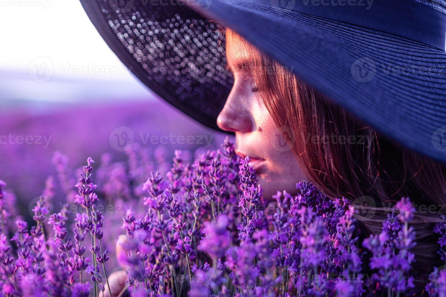 Woman lavender field. Happy carefree woman in black dress and hat with large brim smelling a blooming lavender on sunset. Perfect for inspirational and warm concepts in travel and wanderlust. Close up photo