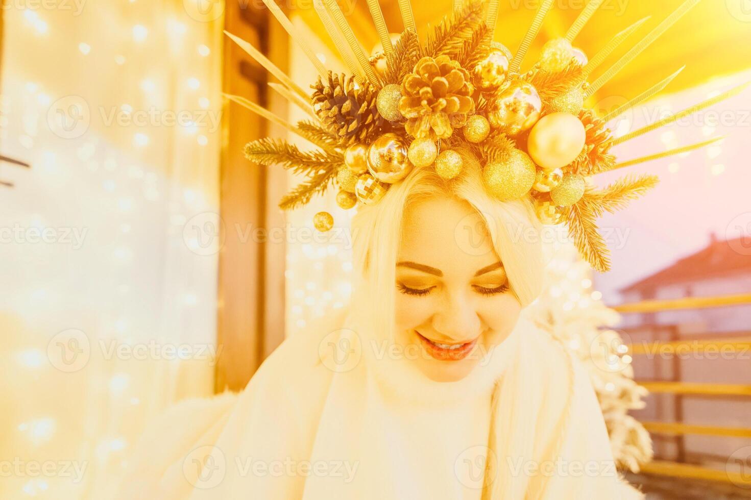 A woman in a white dress is holding a gold box with a red ribbon. She is wearing a crown on her head. The woman appears to be opening the gift box. photo