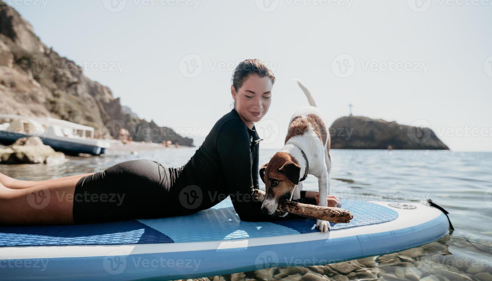 Sea woman sup. Silhouette of happy positive young woman with her dog, surfing on SUP board through calm water surface. Idyllic sunset. Active lifestyle at sea or river. Summer vacation with pets. photo