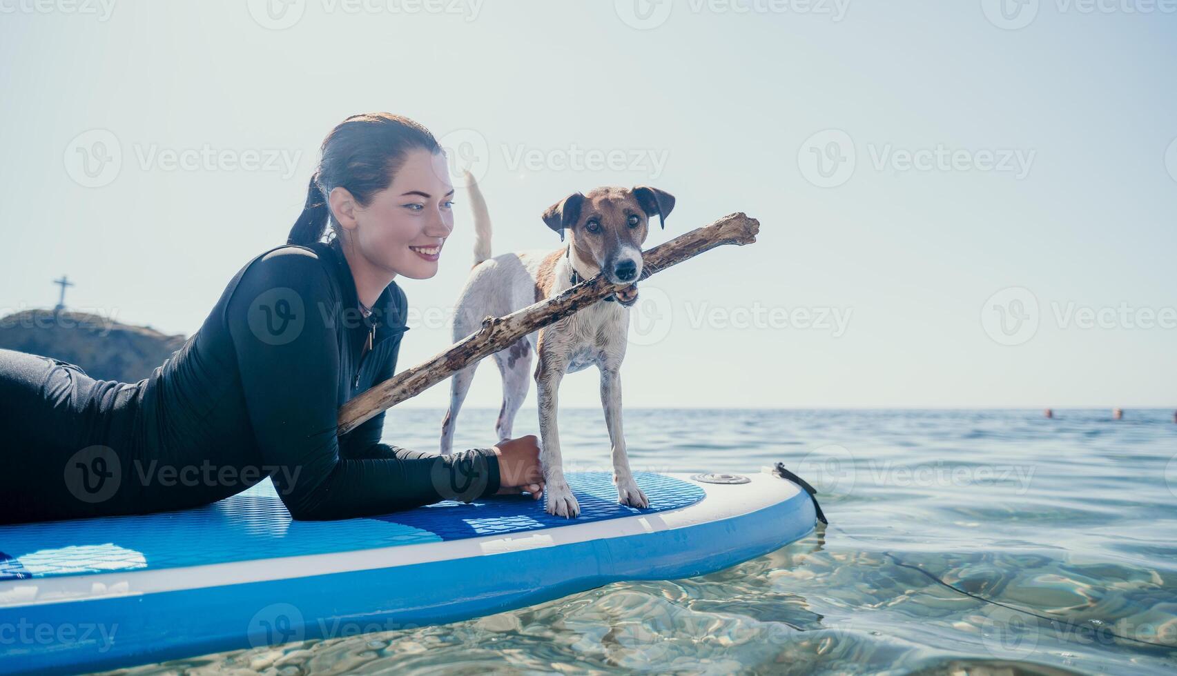 Sea woman sup. Silhouette of happy positive young woman with her dog, surfing on SUP board through calm water surface. Idyllic sunset. Active lifestyle at sea or river. Summer vacation with pets. photo