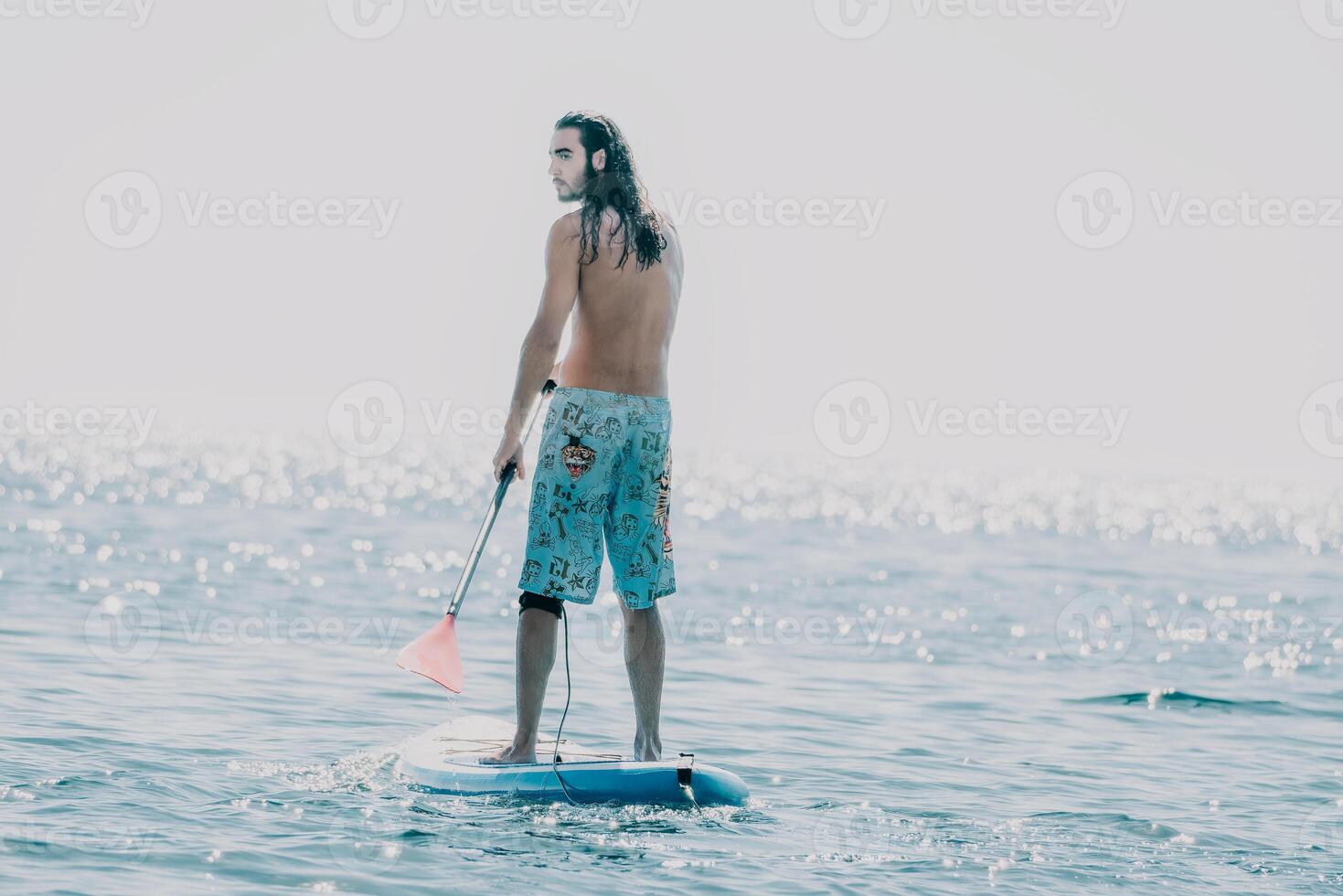 Man Sup Sea. Strong athletic man learns to paddle sup standing on board in open sea ocean on sunny day. Summer holiday vacation and travel concept. Aerial view. Slow motion photo