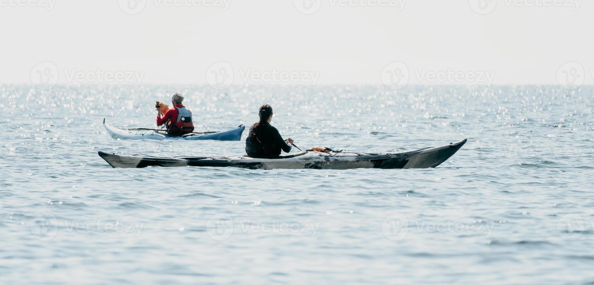 Man woman sea kayak. Happy free man and woman in kayak on ocean, paddling with wooden oar. Calm sea water and horizon in background. Active lifestyle at sea. Summer vacation. photo