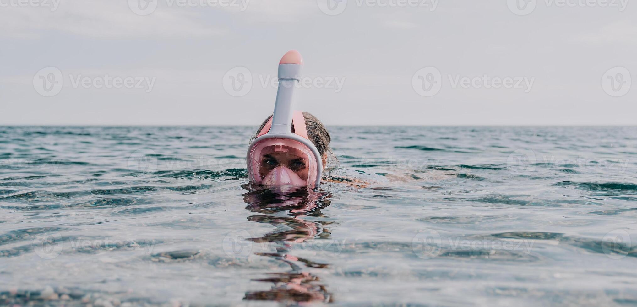 Young happy woman in white bikini and wearing pink mask gets ready for sea snorkeling. Positive smiling woman relaxing and enjoying water activities with family summer travel holidays vacation on sea. photo