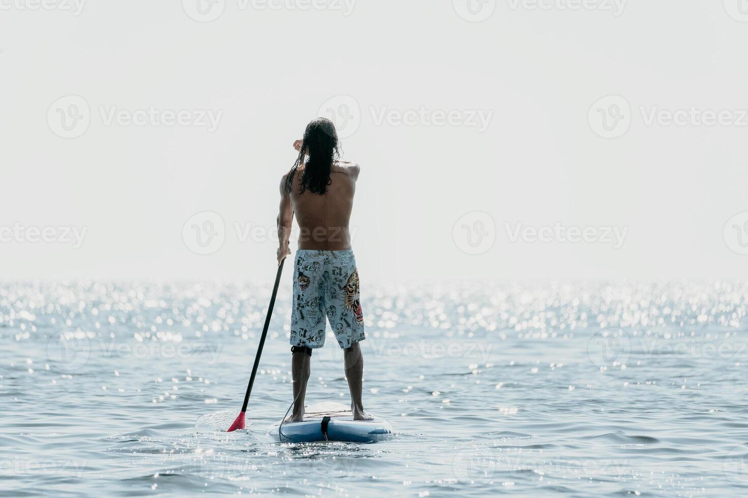 Man Sup Sea. Strong athletic man learns to paddle sup standing on board in open sea ocean on sunny day. Summer holiday vacation and travel concept. Aerial view. Slow motion photo