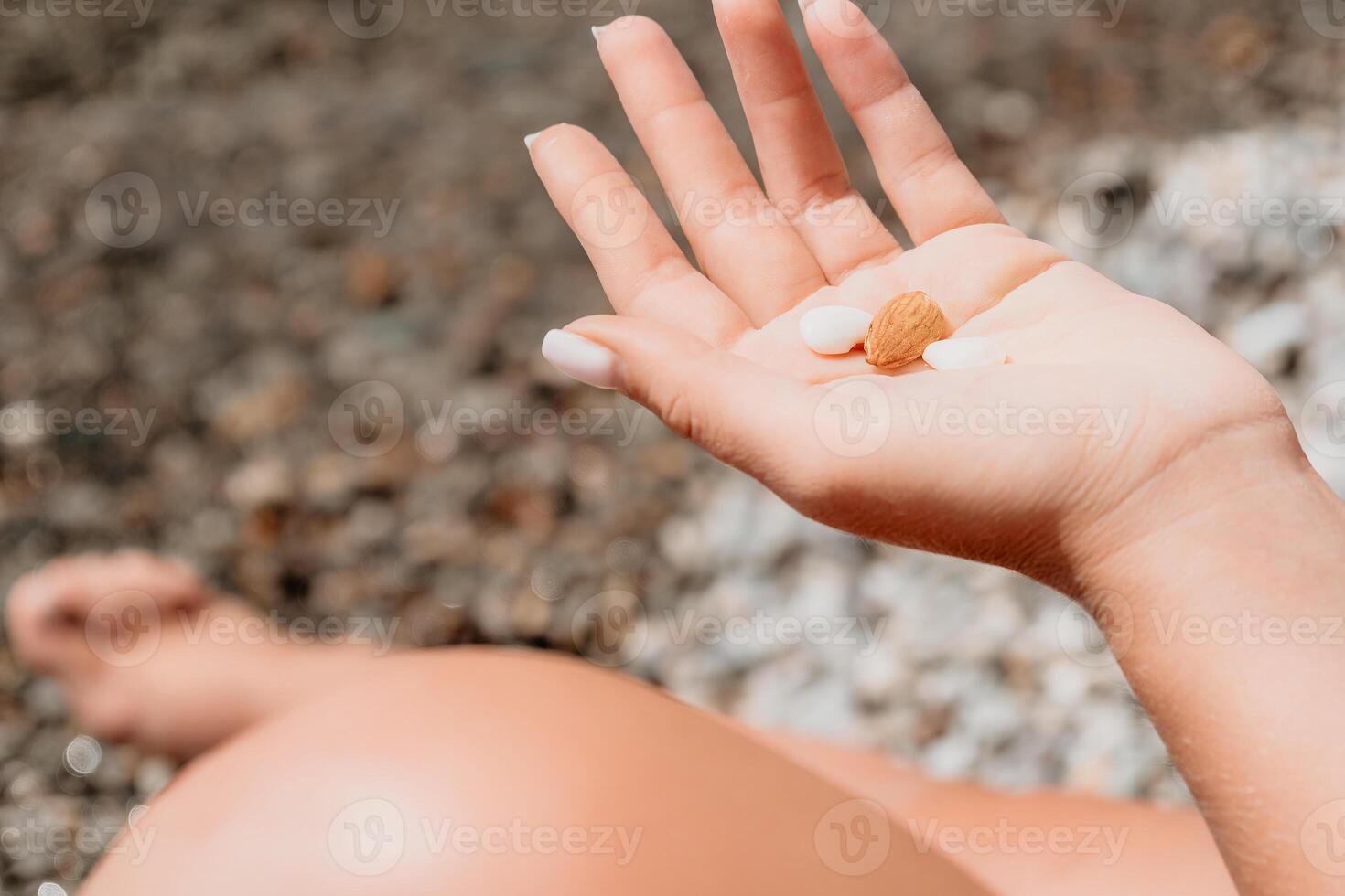 Woman eating milky almond nuts. A young caucasian woman chopping fresh green almond after morning fitness yoga near sea. Only hands are visibly. Healthy vegan food. Slow motion. Close up photo