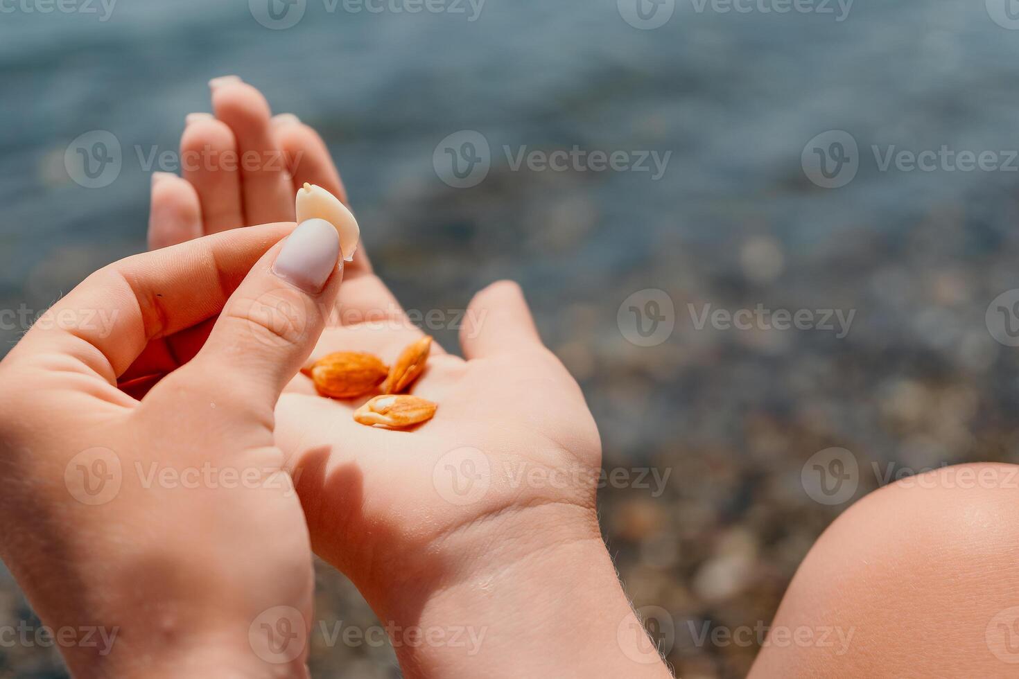 Woman eating milky almond nuts. A young caucasian woman chopping fresh green almond after morning fitness yoga near sea. Only hands are visibly. Healthy vegan food. Slow motion. Close up photo