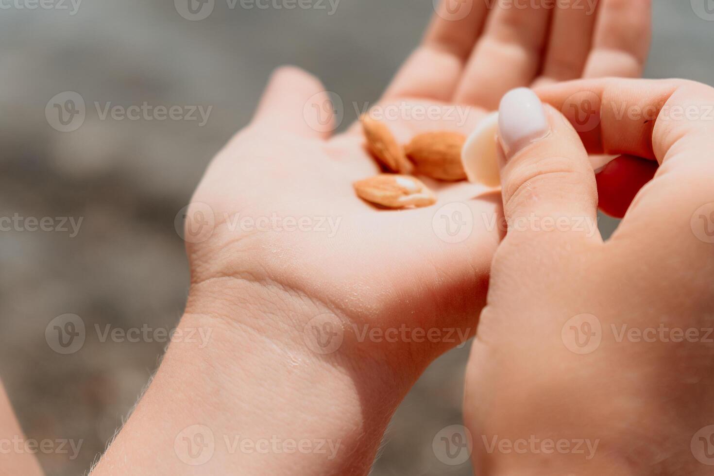 Woman eating milky almond nuts. A young caucasian woman chopping fresh green almond after morning fitness yoga near sea. Only hands are visibly. Healthy vegan food. Slow motion. Close up photo