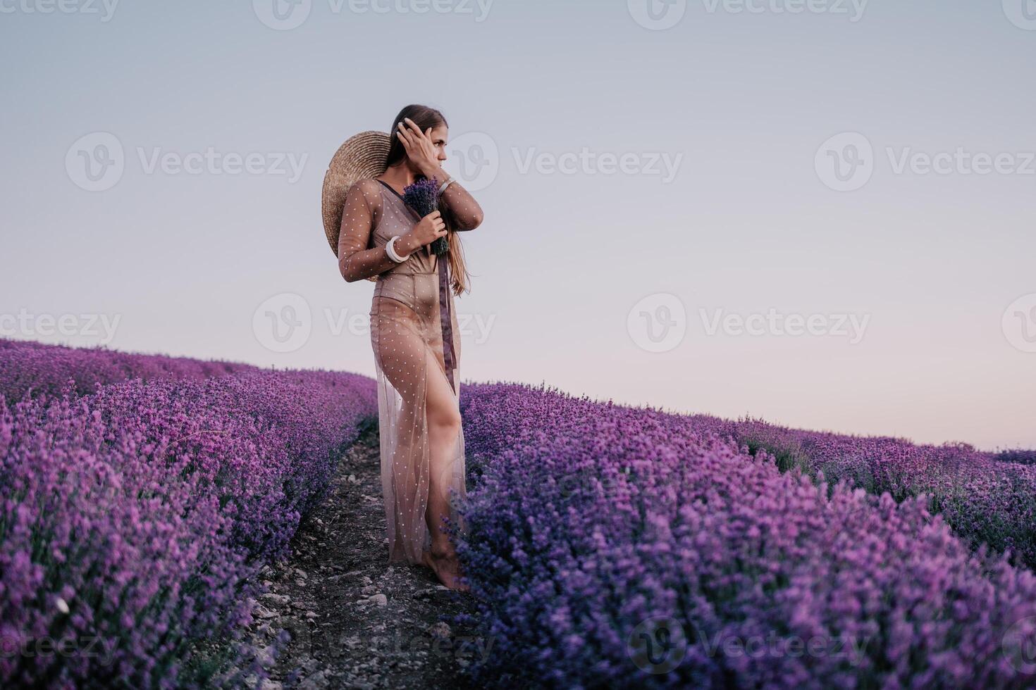 Woman lavender field. Happy carefree woman in beige dress and hat with large brim smelling a blooming lavender on sunset. Perfect for inspirational and warm concepts in travel and wanderlust. Close up photo