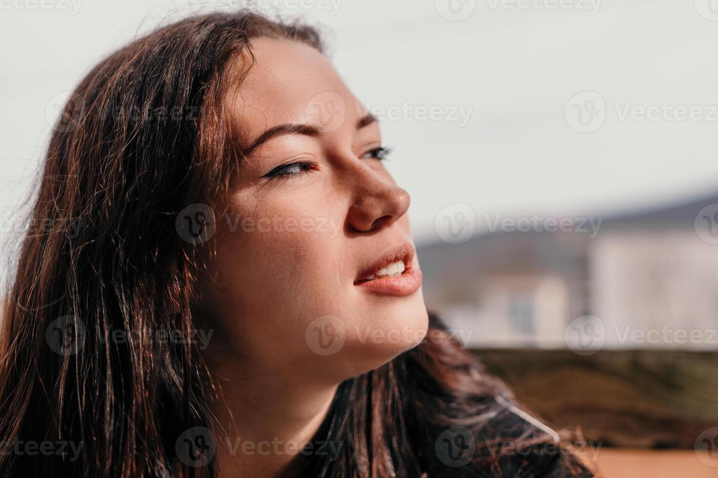 Happy young smiling woman with freckles outdoors portrait. Soft sunny colors. Outdoor close-up portrait of a young brunette woman and looking to the camera, posing against autumn nature background photo