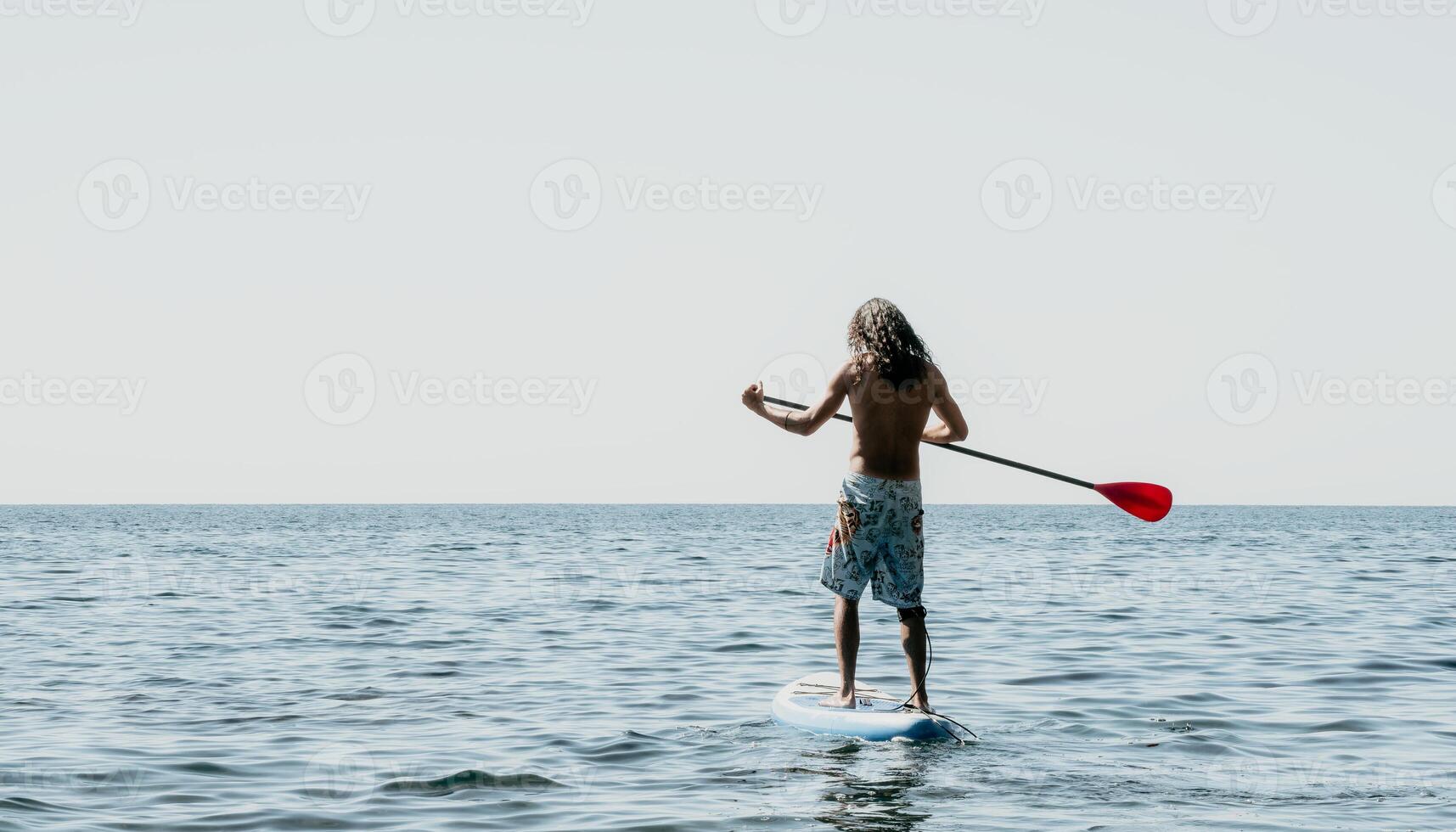 Man Sup Sea. Strong athletic man learns to paddle sup standing on board in open sea ocean on sunny day. Summer holiday vacation and travel concept. Aerial view. Slow motion photo