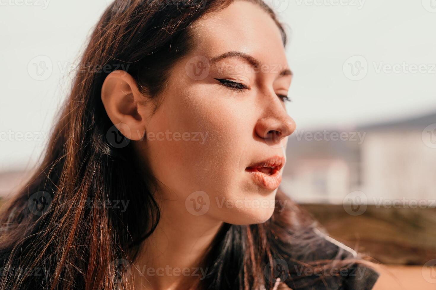 Happy young smiling woman with freckles outdoors portrait. Soft sunny colors. Outdoor close-up portrait of a young brunette woman and looking to the camera, posing against autumn nature background photo